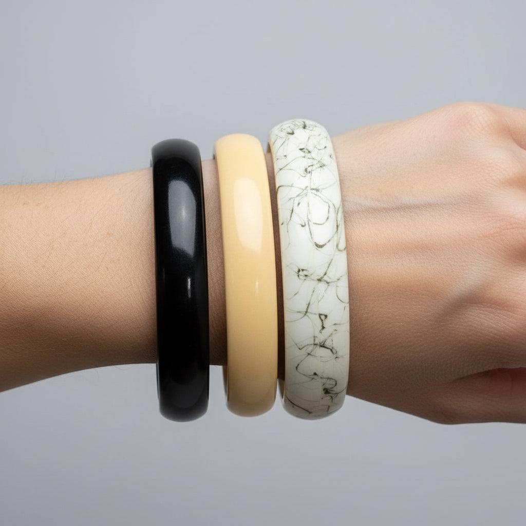 Vintage resin bangle set of 3 held in hand showing black, cream and marble bangles